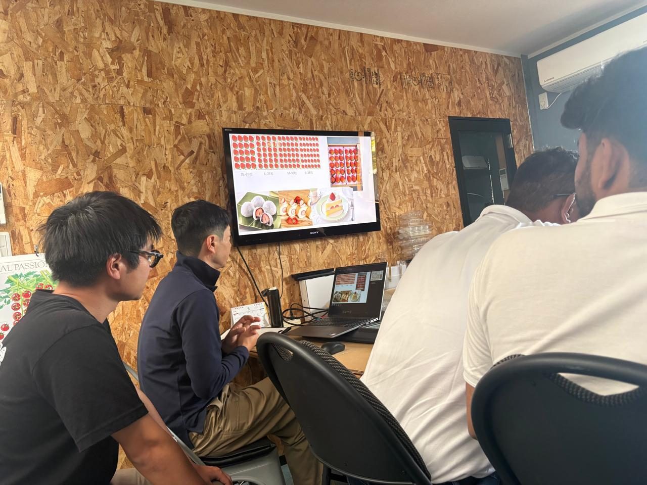 Classroom session at Suzuki Farm — Mr. Suzuki explaining strawberry grading standards and size classes on screen